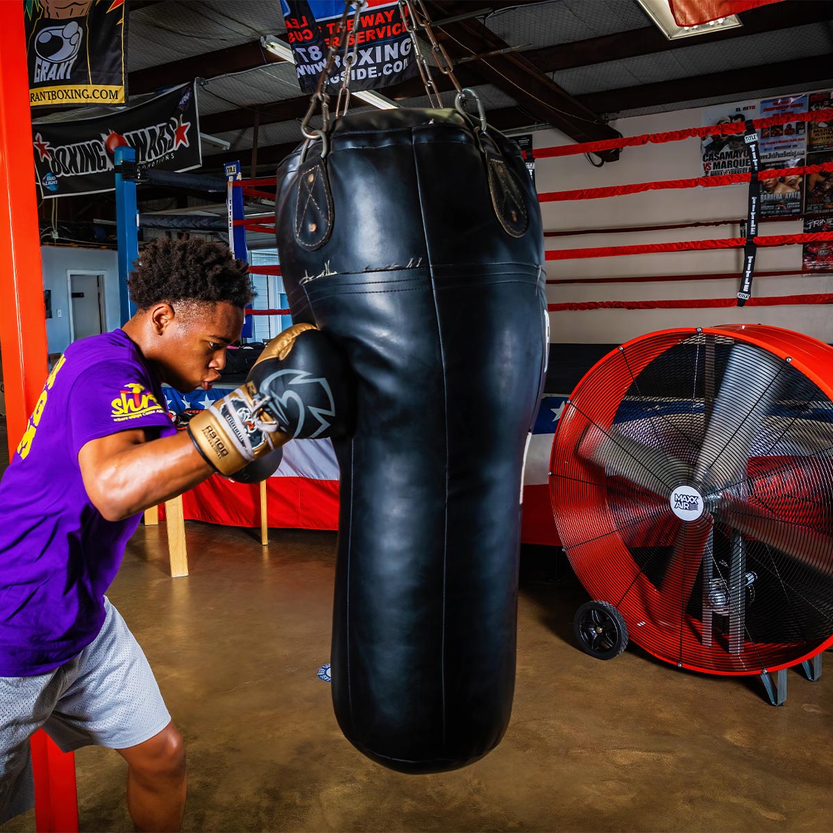 The Maxx Air 48 inch red drum fan cools a boxer during gym practice, providing high volume air movement.