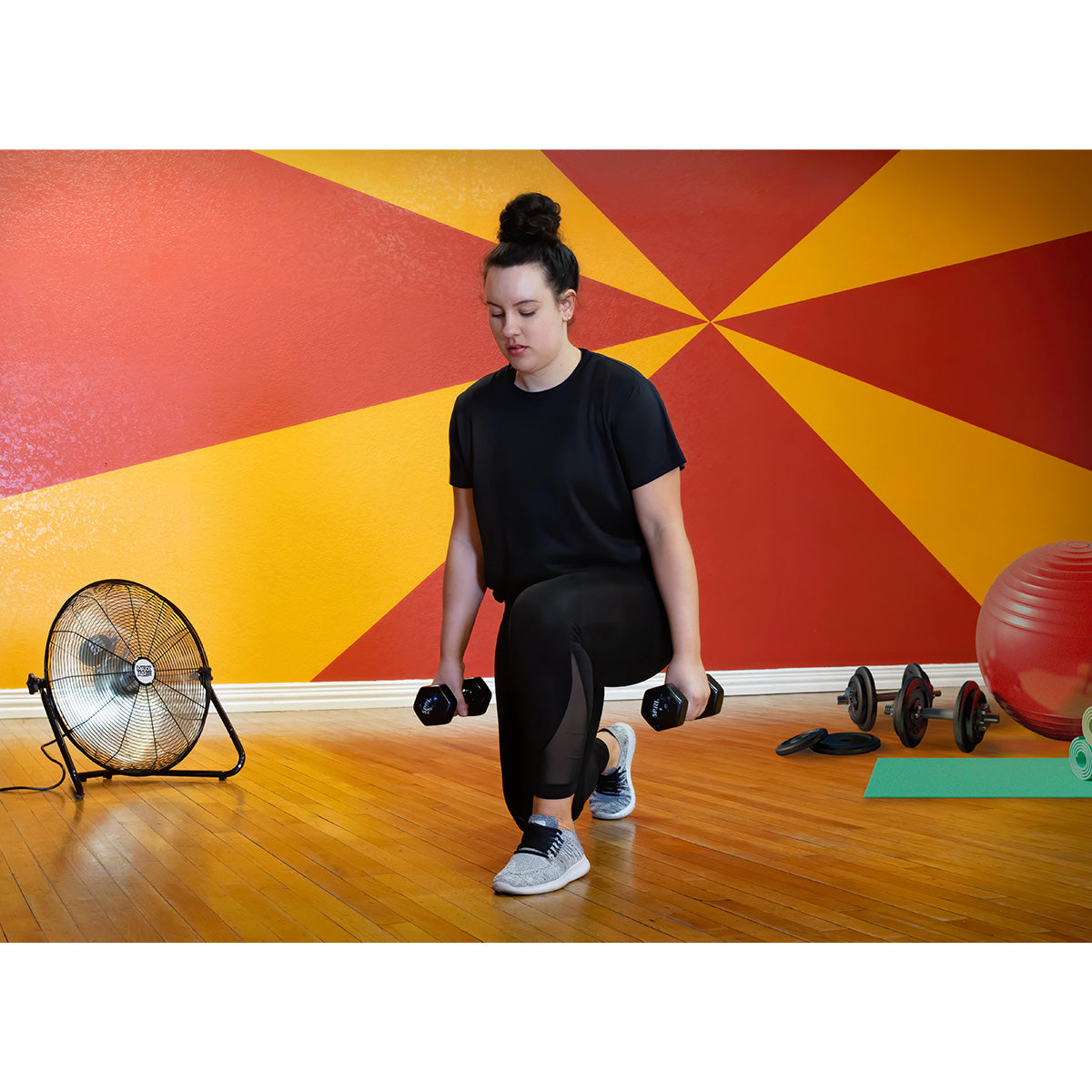 The heavy duty 20 in. floor fan cools a woman during a gym workout.