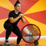 30 in. barrel fan cools woman working out in a gym.