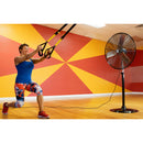 Commercial pedestal fan unit cooling an athlete in a large room during a gym workout. 